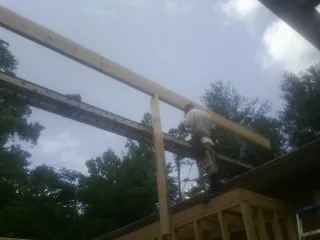 Carpenter setting a ridge beam over a new addition frame — Ice Dam Removal by Roofing Brothers in Colusa