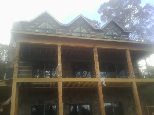 Dormers and porch framing on a large log home under construction — Roof Coating work by our crew in Colusa