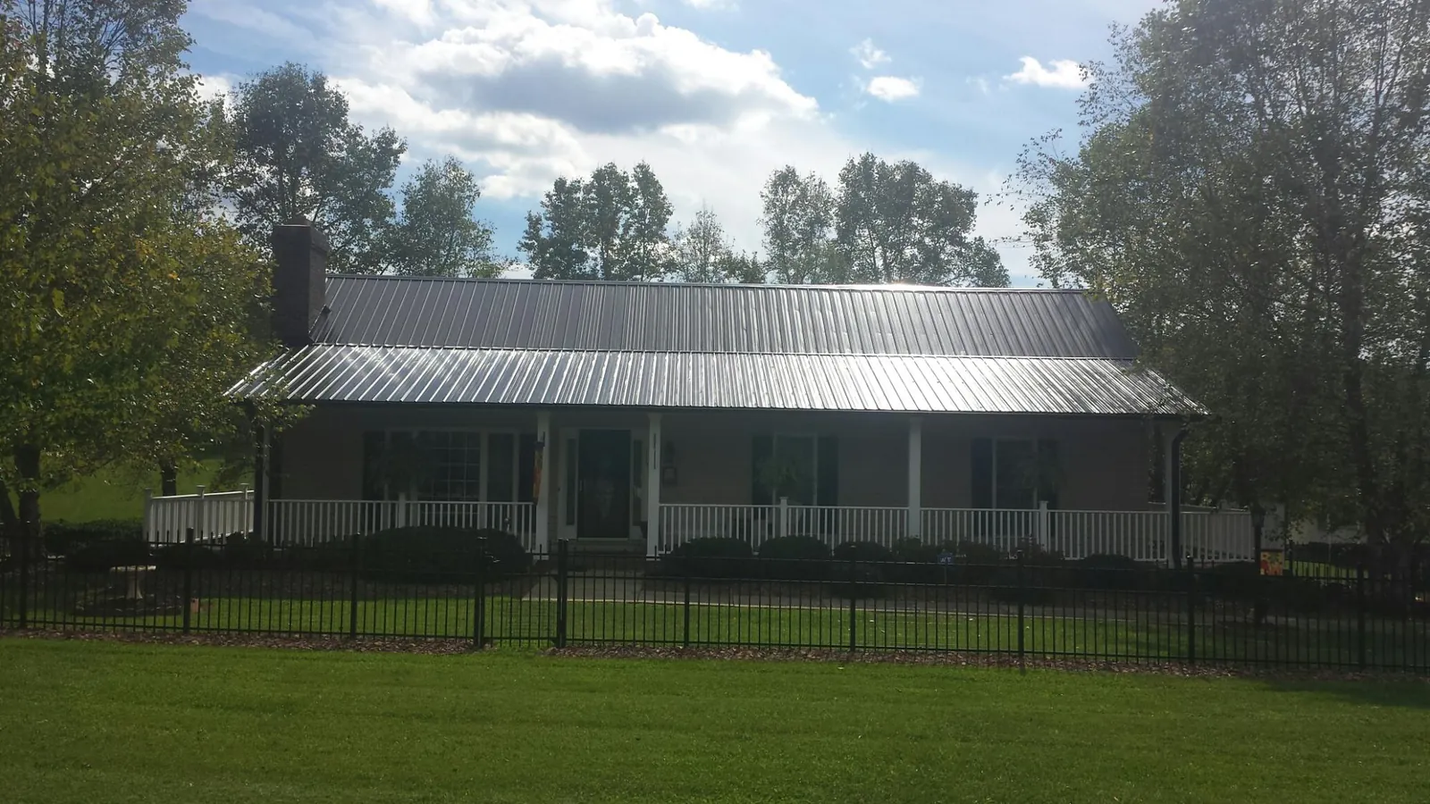 Gray metal roof on a brick ranch with a full width front porch — Gutter Guard Installation work by our crew in Colusa