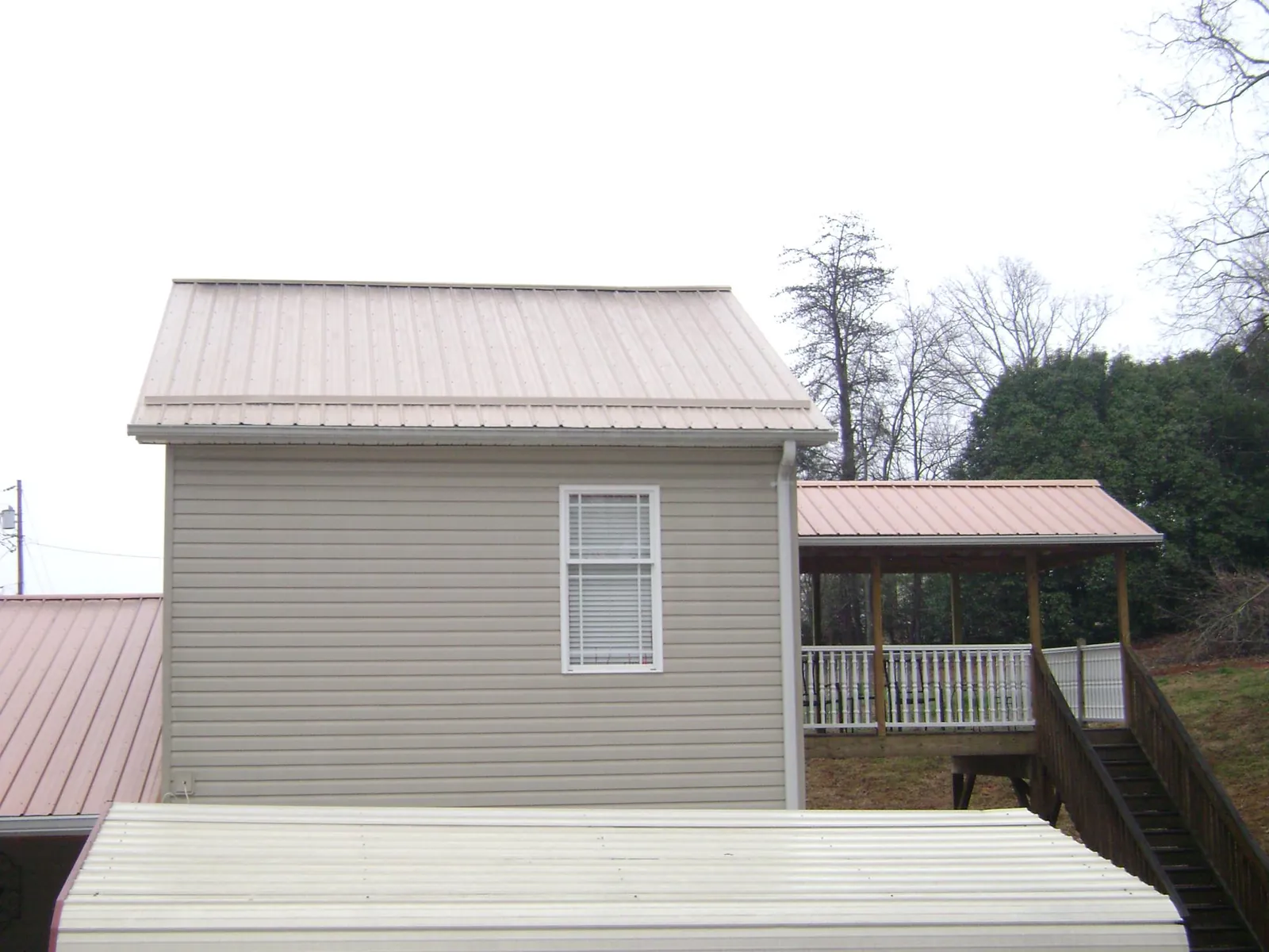 Tan metal roofs on a two story addition and attached porch, from a Roof Replacement job in Colusa